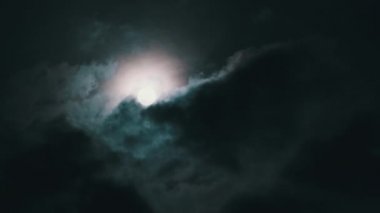 Gece gökyüzündeki dolunay kara bulutların arasında hareket eder, Timelapse. Mistik parlak ay bulutların arka planına doğru yükseliyor. Ay ışığı karanlık gece gökyüzünde parlar. Zaman aşımı. 4K