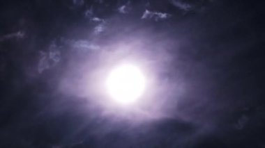 Gece gökyüzündeki dolunay kara bulutların arasında hareket eder, Timelapse. Mistik parlak ay bulutların arka planına doğru yükseliyor. Ay ışığı karanlık gece gökyüzünde parlar. Ayın doğumu zaman aşımı. 4K