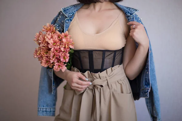 Bej bluzlu kız, korse, pantolon ve kot ceketli.