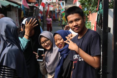 Jakarta, Endonezya - 12 04 2020: Bir erkek ve birkaç kadın çitin önünde kameraya poz veriyor