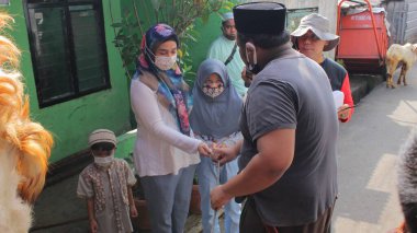 Jakarta, Endonezya - 07 31 2020: Bir anne ve çok sayıda çocuk, Kurban Bayramı 'nda qabul yapmak için izin almak üzere qurban organizatörlerinden biriyle tokalaşıyor