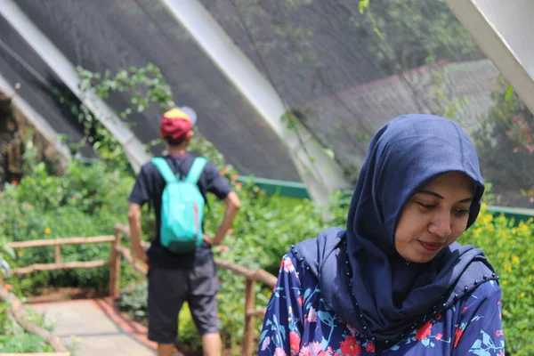 Jakarta, Endonezya - 12: 24 2020: Başörtüsü takan bir kadın Taman Mini Indonezya Indah bahçesinde tatildeyken aşağı bakar ve gülümser, Jakarta
