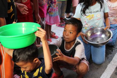 Jakarta, Endonezya - 08 17 2018: 72. Endonezya Bağımsızlık Günü 'nde suyu bir konteynırdan diğerine taşırken tuhaf bir ifade takınan çocuk