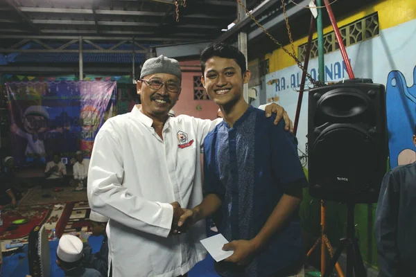 Jakarta, Endonezya - 05: 26: 2019: Ramazan ayındaki yetimhane kutlamaları sırasında hediye vermek için tokalaşan bir baba ve genç adamın mutlu ifadeleri