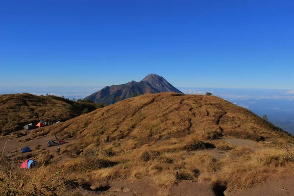 Kahverengi çimen manzarası ve Merbabu Dağı 'nın tepesine uzanan gökyüzü.