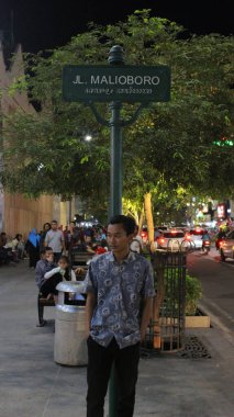 Yogyakarta, Endonezya - 08 07 2019: Yogyakarta, Central Java 'da tatildeyken gece sokak ismi direğinde duran adam