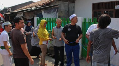 Jakarta, Endonezya - 08 11 2019: Jakarta sokaklarında düzenlenen Kurban Bayramı kutlamaları sırasında kurban edilen hayvanları kurban etmek için ipleri tutan qurban hayvan bağışçıları