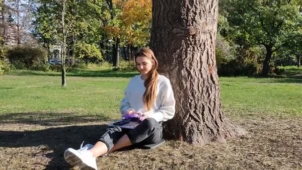 스웨터를 공원에서 음악을 소녀가 근처에 자주색 글자로 음악을 여자아이 공원의 — 비디오
