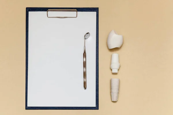 牙科植入物和夹子夹在米色背景的A4纸片上 义齿种植体模型 牙科和医疗用品的概念 图片与地方为您的文字和设计 — 图库照片