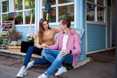 Bahçedeki ahşap evin yakınındaki basamaklarda oturan bir kıza sarılan adam.