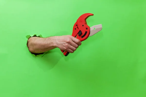 Man Holds Tool Cutting Plastic Pipes Green Background — ストック写真