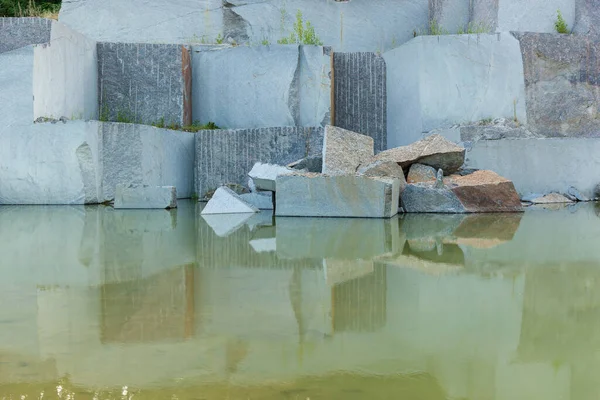 Granite quarry with large granite blocks Abandoned granite quarry with rain water. Granite mining in a quarry.