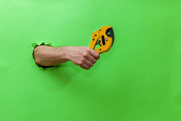 Man Holds Tool Cutting Plastic Pipes Green Background — 图库照片