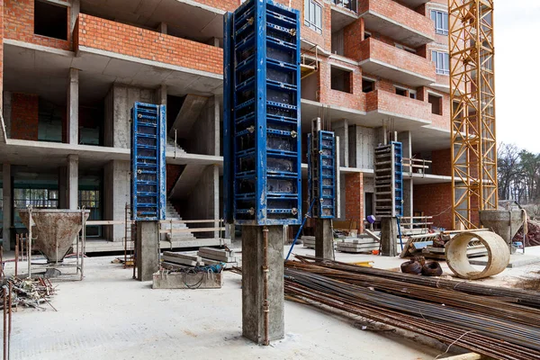 Industrial building, foundation, pillars, formwork, reinforced concrete structures against the background of a brick multi-storey building. Construction site with reinforced concrete structures