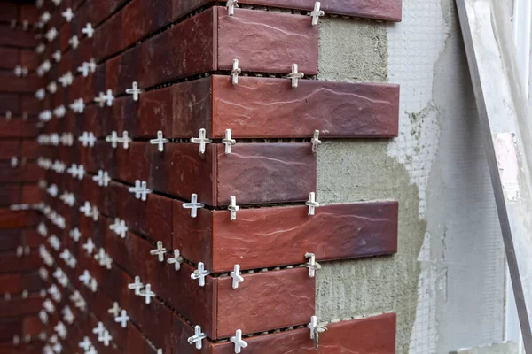 Installation of facing facade tiles on the wall of the house