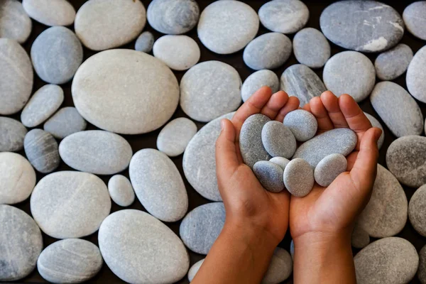 孩子们的手拿着石头放在他们的手掌上 后面是用轻石做成的圆石子 — 图库照片