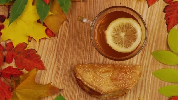 Осенний чай с ломтиком лимона и круассаном. Осенние листья, на деревянном столе. Вращения . — стоковое видео