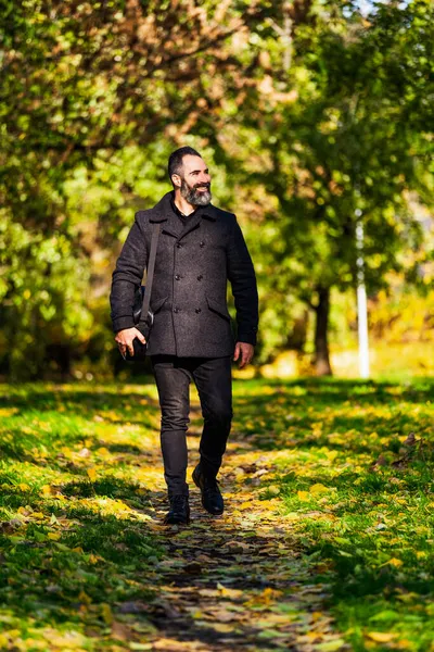 幸せなビジネスマンは秋に公園を歩いている 彼は太陽と新鮮な空気を楽しんでいる — ストック写真