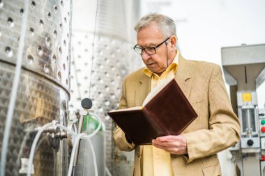 Şaraphane sahibi kıdemli bir adamın portresi. Şarap deposunun yanında duruyor ve soğutma işlemini inceliyor..