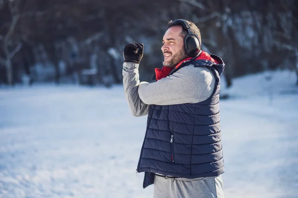 大人の男は冬に公園で運動している ジョギングの前に体を伸ばしている — ストック写真