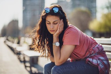 Üzgün genç bir kadın kentte bankta oturuyor. Morali bozuk..