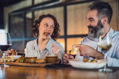 Yetişkin çift restoranda oturuyor. Şarapla yemek yiyorlar ve birlikte güzel vakit geçiriyorlar..