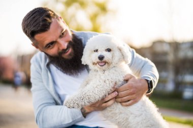 Yetişkin bir adam köpeğiyle güneşli bir günün tadını çıkarıyor..