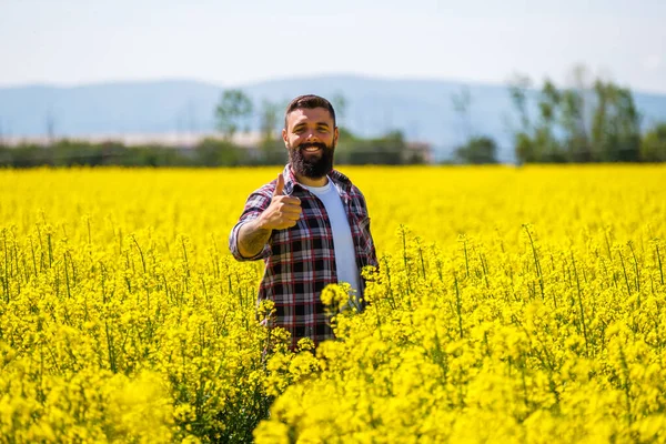 彼の菜種畑に立っている幸せで成功した農民の肖像画 花の中の菜の花 — ストック写真