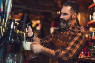 Bardaki barmenlerin portresi. Bira bardağına bira doldurur..