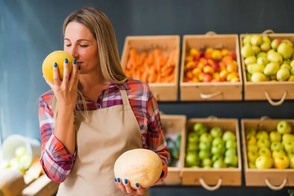 Woman works in fruits and vegetables shop. She is examining goods.