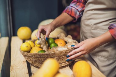 Kadın meyve ve sebze dükkanında çalışıyor. Mağaza vitrinine mal yığıyor..