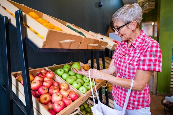 Mature woman buying goods in fruits and vegetables shop.