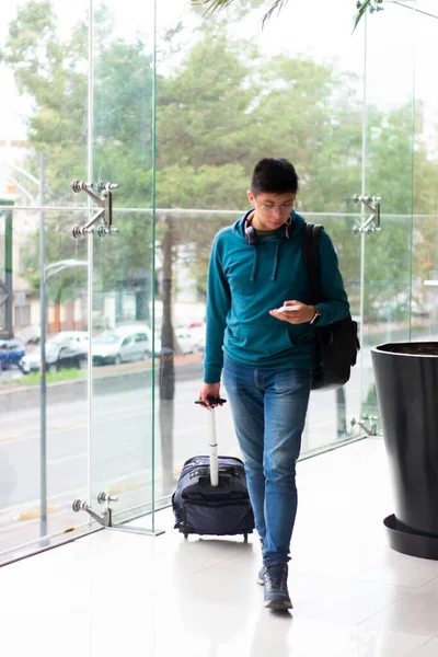 young man walking at Airport with suitcase and smartphone