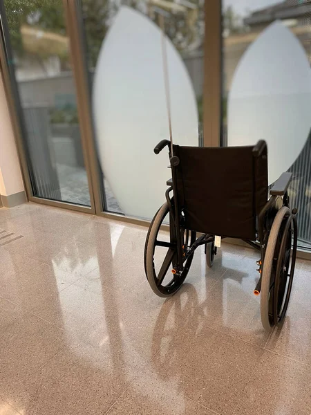 Bir hastanenin penceresinin önündeki boş tekerlekli sandalyeyi kapat.