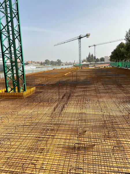 Arka planda üç kule vinci olan bir inşaat sahasında çelik dövmesi.