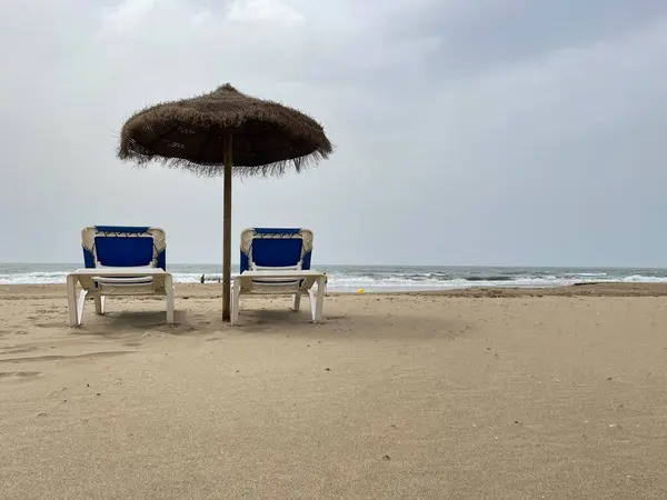 İki sandalye ve deniz tabanlı bir şemsiye. Plaj ve yaz tatili konsepti