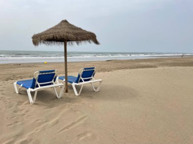 İki mavi güneş pansiyonu ve kumsalda bir şemsiye. Yaz tatilini sahilde geçirmeyi düşün. 