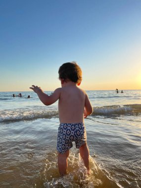 Çocuk yaz tatilinde sahilde deniz suyunda oynuyor. Mutlu çocuk tropik bir plajda açık hava yaşam tarzını seviyor.. 