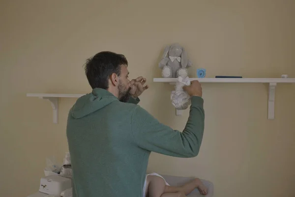 40-year-old father changing diaper of his newborn son. Family life of single father. Father can't stand the smell of his baby's poopy diaper.