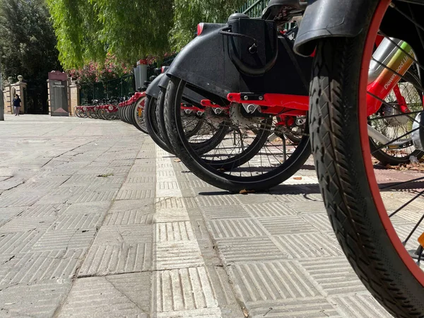 Close-up of electric bicycle wheels parked in an on-street parking lot