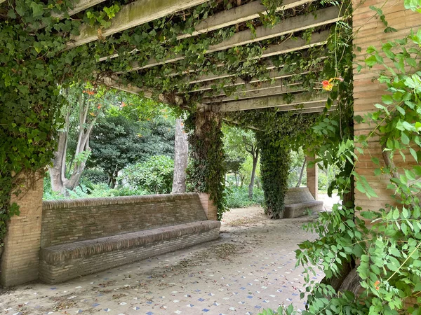 Lush, green garden with stone pergola and stone seats