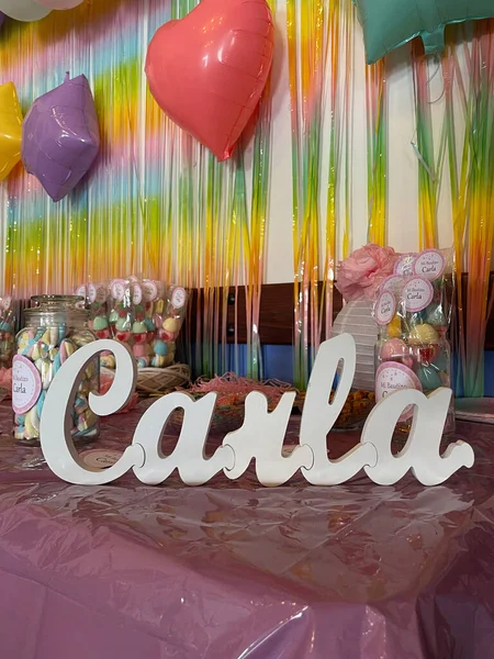 Colorful balloons, streamers, party props and knick-knacks on a pink table with Carla's name on it