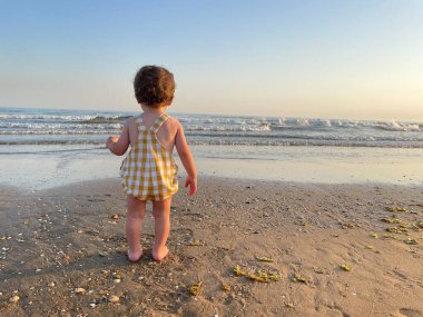 Tanınmayan bir çocuk turistin günbatımını seyredişinin arka görüntüsü gökyüzünü aydınlatıyor. Güneşin okyanusa battığı sahilde özgürlüğün tadını çıkarıyorum..