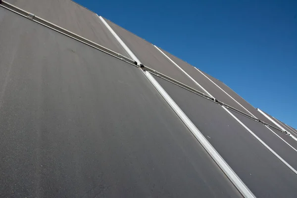 Fotovoltaik panellerle kaplı bir binanın çatısında. Evin çatısındaki güneş panelleri ya da su ısıtma suyu. Yeşil enerji.