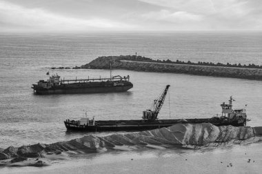 Mafra, Portekiz. 16 Temmuz 2022 gemileri bir okyanus limanının dibindeki kumu temizliyor.