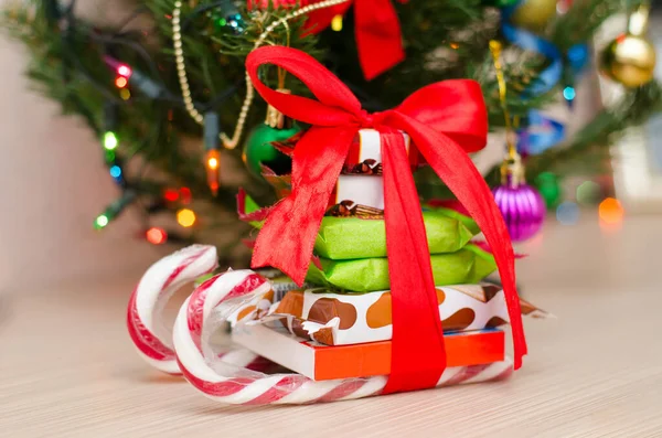 Kırmızı kurdele ve şekerli Noel ağacı ve kızak hediyesi.