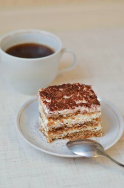 Bir parça çikolatalı kek tiramisu, kahve ve beyaz ahşap arka planda bir fincan çay.
