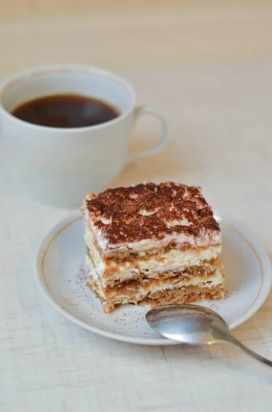 Piece of chocolate cake tiramisu with coffee and cup of tea on white wooden background