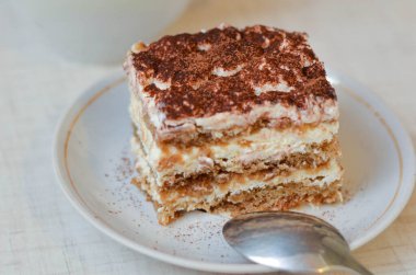 Bir parça çikolatalı kek tiramisu, kahve ve beyaz ahşap arka planda bir fincan çay.