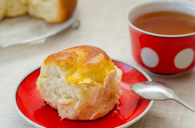 Bir dilim limonlu turta ve kırmızı tabakta bir fincan çay.